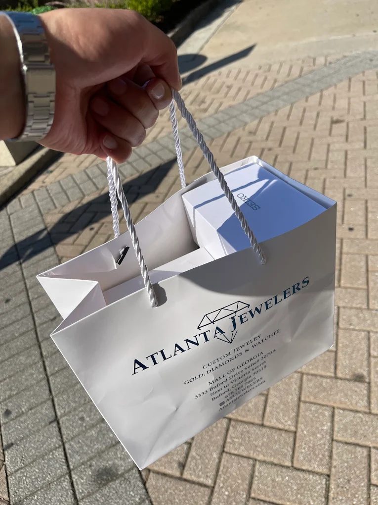 An Atlanta Jewelers gift bag with a boxed watch inside, carried outside the mall