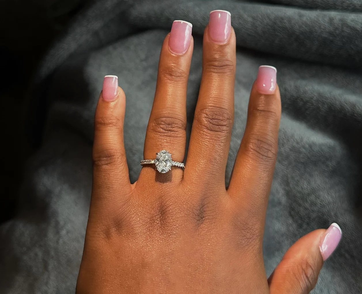 A customer's hand wearing an oval diamond engagement ring with a pavé band from Atlanta Jewelers