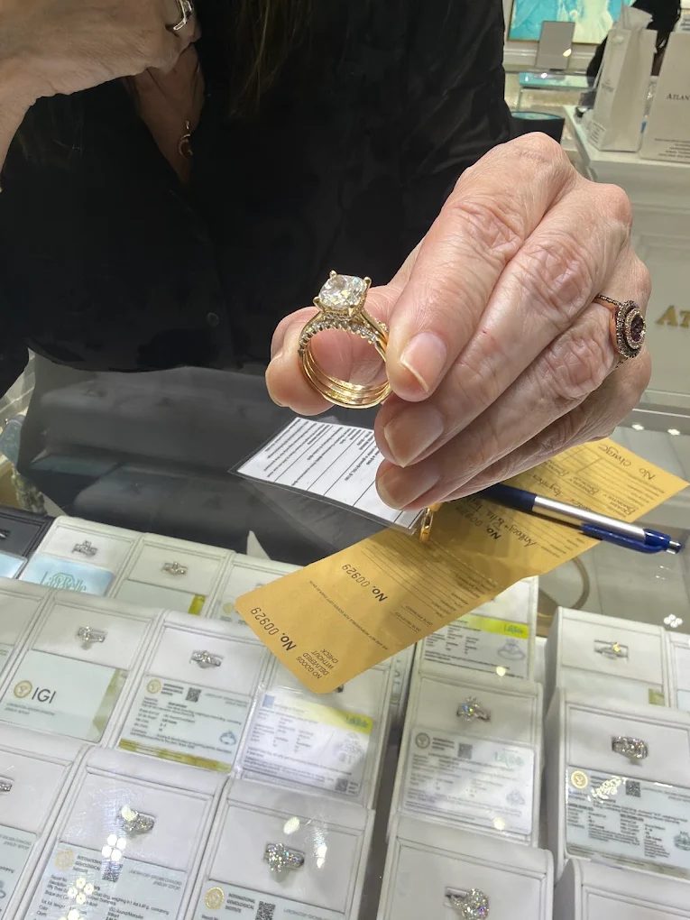 Our jeweler holding a yellow gold diamond engagement ring over the display case at Atlanta Jewelers